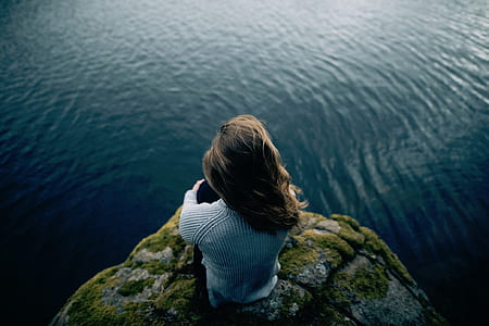 woman in gray striped shirt standing on cliff thumbnail