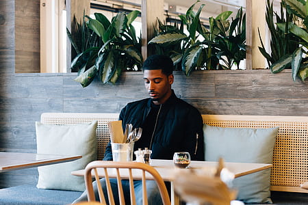 man in black jacket sitting on couch in front of table thumbnail