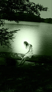 woman sitting on tree stem near body of water thumbnail