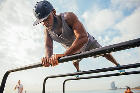 A young African man doing push-ups on bars on the beach thumbnail