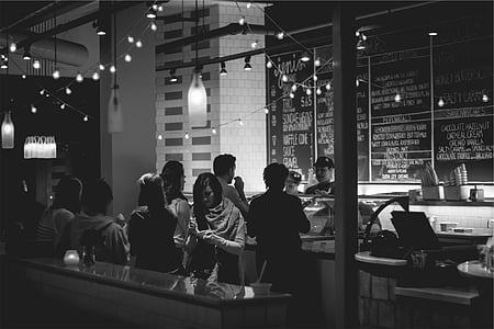 grayscale photo of people standing near table thumbnail