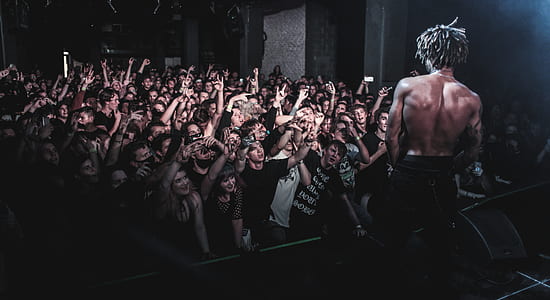 man standing on stage facing group of people raising hands thumbnail