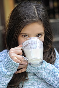 girl drinking white liquid from clear glass mug thumbnail