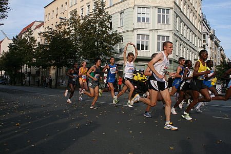 people running on roadway near white concrete building during daytime thumbnail