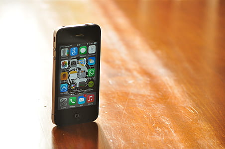 black iPhone 4 displaying interface screen and placed on brown wood surface thumbnail