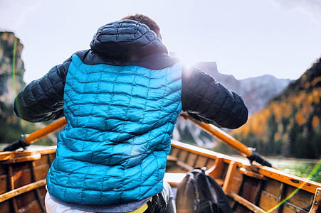 Man in Blue Vest Holding Paddle Sitting Inside Boat thumbnail