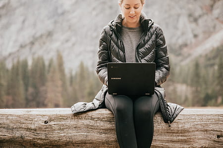 woman sitting on tree trunk with laptop on her lap thumbnail