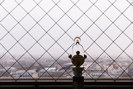 brown and white telescope beside black fence near buildings under white sky at daytime thumbnail