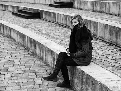 woman wearing black coat sitting on gray surface thumbnail