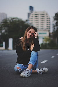 woman wearing jeans sitting down on asphalt road thumbnail