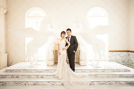 wedding couple standing on stage beside rearing horse statues thumbnail