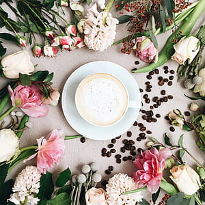 cup filled with coffee on top of saucer surrounded by flowers thumbnail