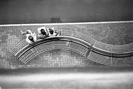 three person sitting on bench near road thumbnail