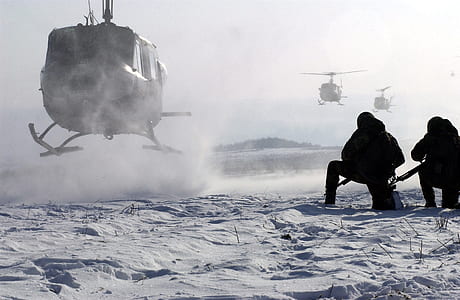 two person kneeling beside helicopter land on snow field thumbnail