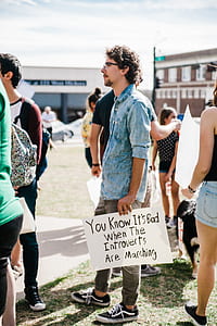 man holding card you know it's bad when the introverts are marching thumbnail