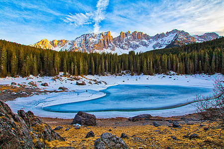 lake near trees and mountain under cloudy sky thumbnail