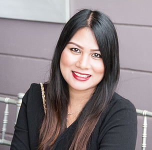 smiling woman sitting on white chair near gray wall thumbnail