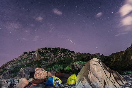 two green-and-blue dome tents on brown rock at nighttime thumbnail