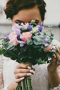 closeup photography of bride holding green button ferns, pink rose flowers, and purple grape hyacinth flowers bouquet thumbnail