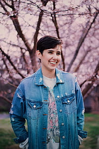 woman wearing blue denim jacket standing near cherry blossom thumbnail