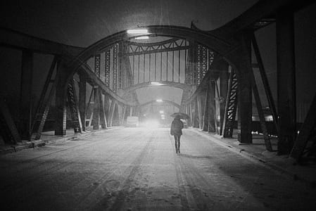grayscale photo of person walking on bridge thumbnail