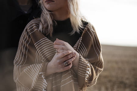 woman wearing brown poncho holding her hands thumbnail