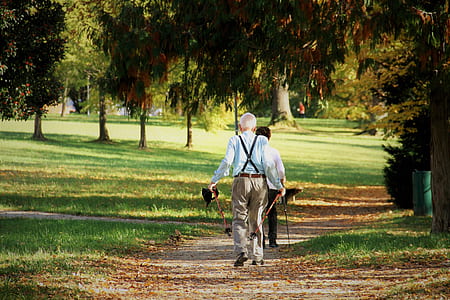 man wearing blue long-sleeved shirt and gray pants holding two red string trimmers during daytime thumbnail