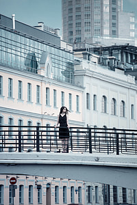 woman in black v neck dress on gray overpass near buildings during daytime thumbnail
