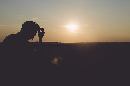 silhouette photo of man touching his hair at open field during daytime thumbnail