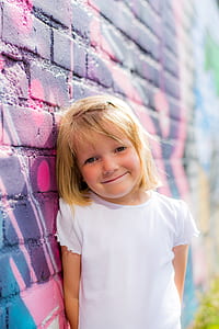 smiling girl leaning on concrete wall thumbnail