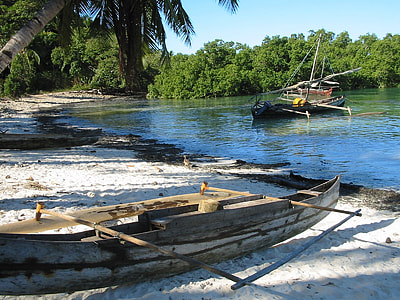 brown canoe on seashore near boat on body of water during daytime thumbnail