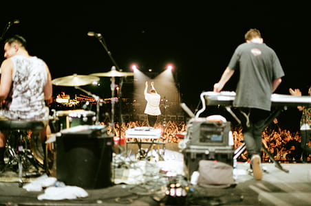 man standing on stage while singing near crowded people at nighttime thumbnail