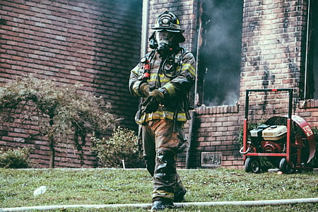 firefighter walking away from building while adjusting gloves during daytime thumbnail