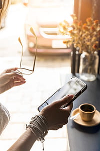 Person Carrying Black Smartphone and Clear Eyeglasses With Black Temples thumbnail