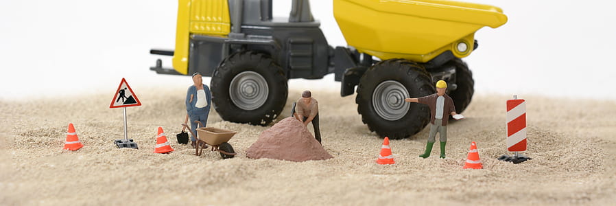 black and yellow tractor with three person figure on white sand thumbnail