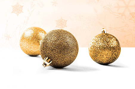 three gold-colored baubles on white surface thumbnail