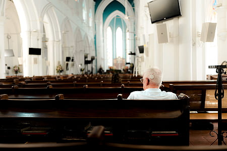 man wearing white shirt sitting on pew bench inside church thumbnail