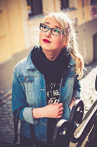 woman wearing black shirt, blue denim button-up jacket, and black framed eyeglasses thumbnail