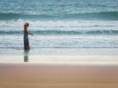 woman walking on seashore during daytime thumbnail