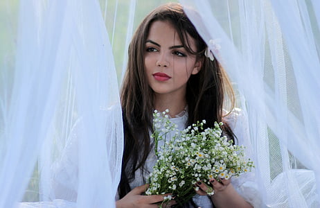woman in white puff-sleeved top holding bouquet of baby's breath flowers thumbnail