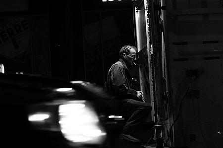grayscale photo of man sitting while smoking thumbnail