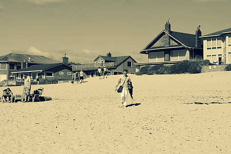 person walking on seashore near houses thumbnail