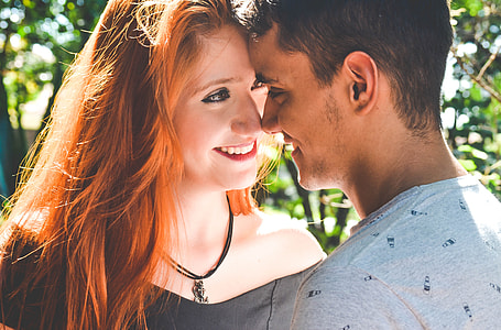 man in gray crew-neck shirt leaning on woman's head near green plants during daytime thumbnail