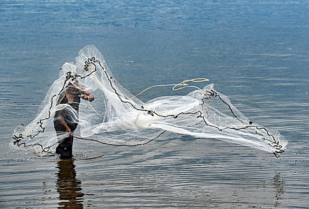 person throwing fishing net on body of water thumbnail