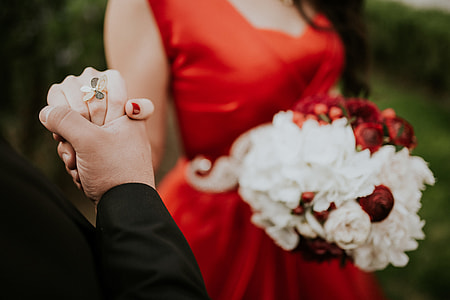 woman in red dress holding flower beside man in black top thumbnail