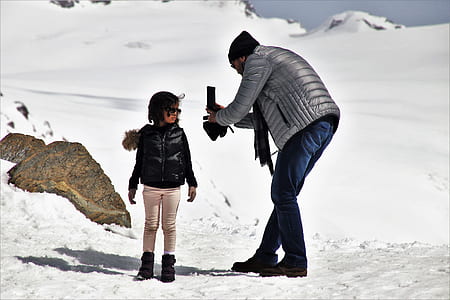 man and girl taking photo on snow field thumbnail
