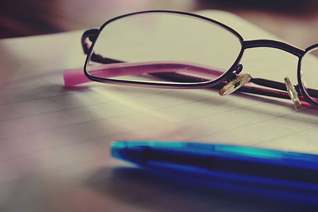 shallow focus photography of eyeglasses beside blue ballpoint pen thumbnail