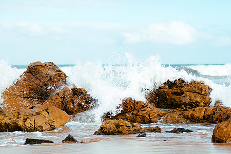 waves crashing on brown rocks thumbnail