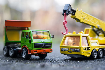 two green and yellow truck toys on gray pavement thumbnail