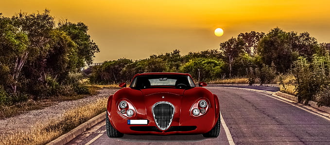 red luxury car on grey asphalt road during orange sunset thumbnail